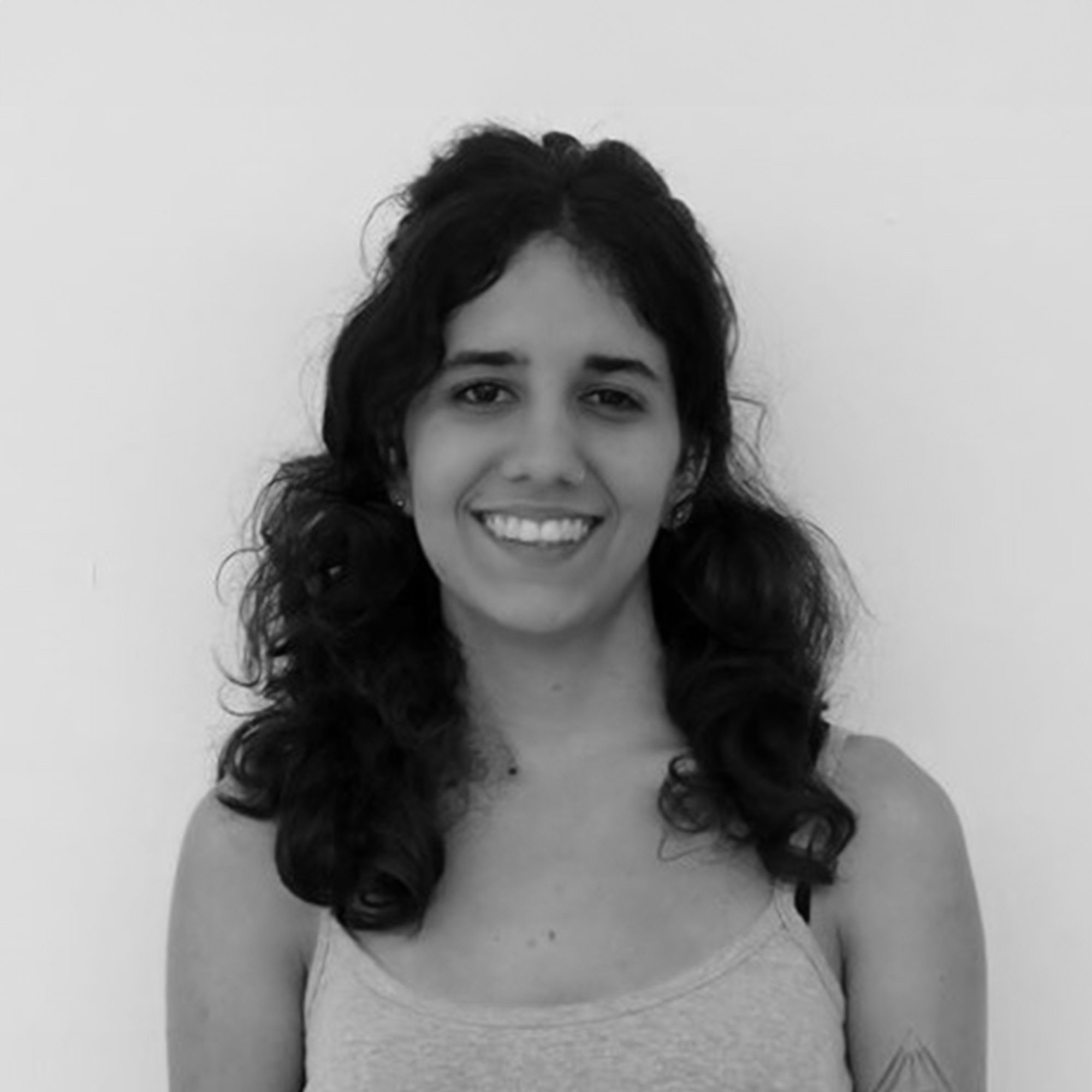 Foto em preto e branco de uma mulher de cabelos morenos. Ela está sorrindo.